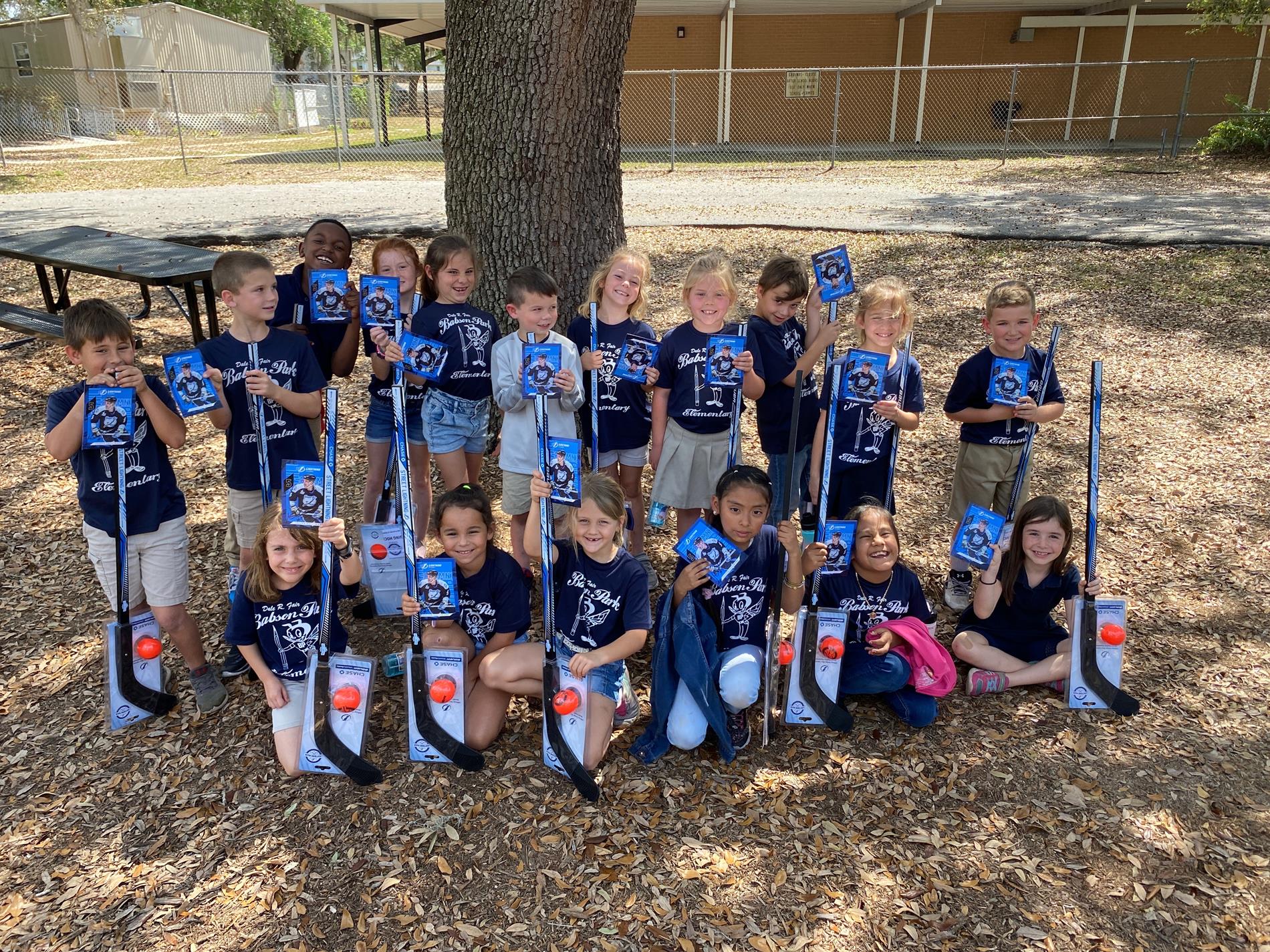 1st grade students with their hockey stick, ball, and autographed card.