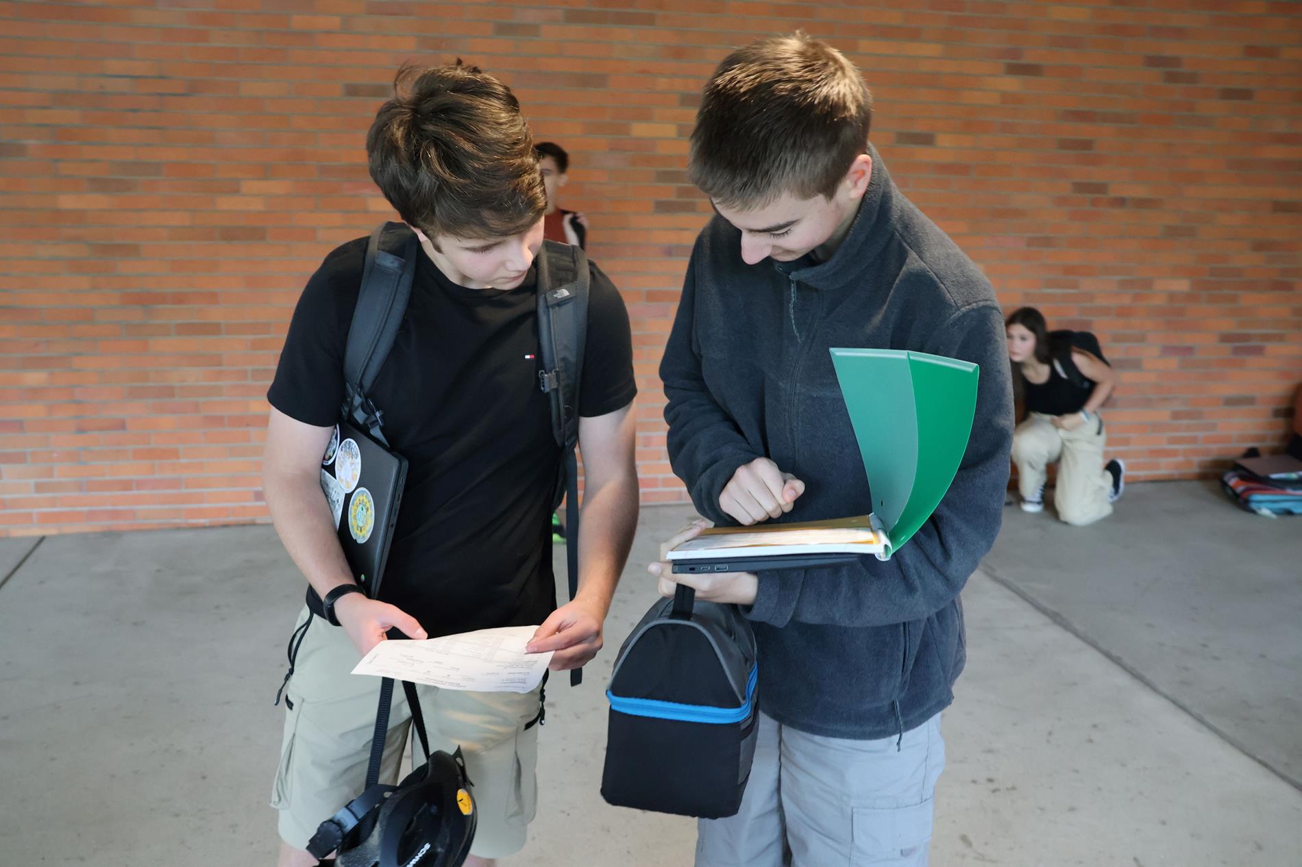 Two students looking at folder of papers outside Jefferson Middle School Building