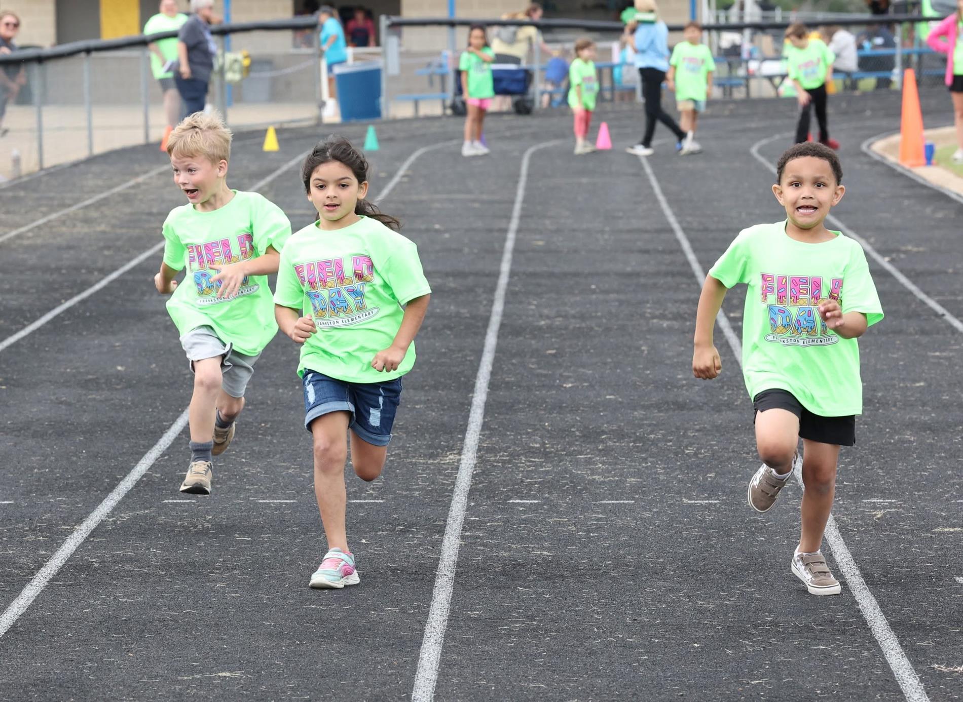 elementary students in green shirt running a race at field day