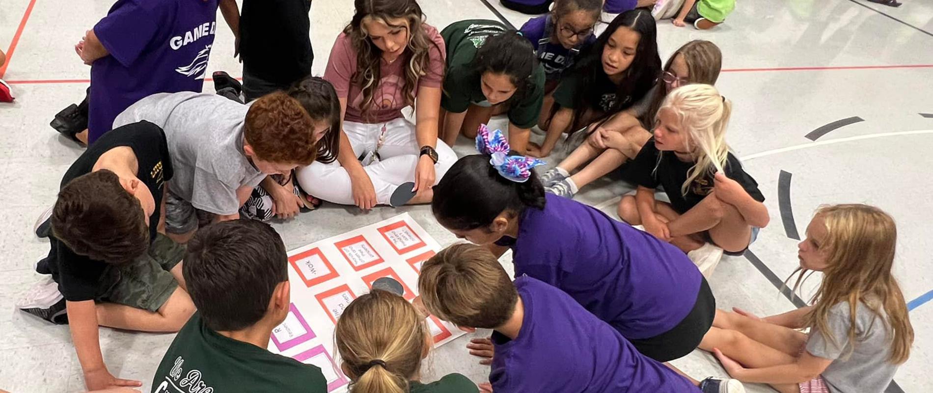 Students playing board game with their teacher