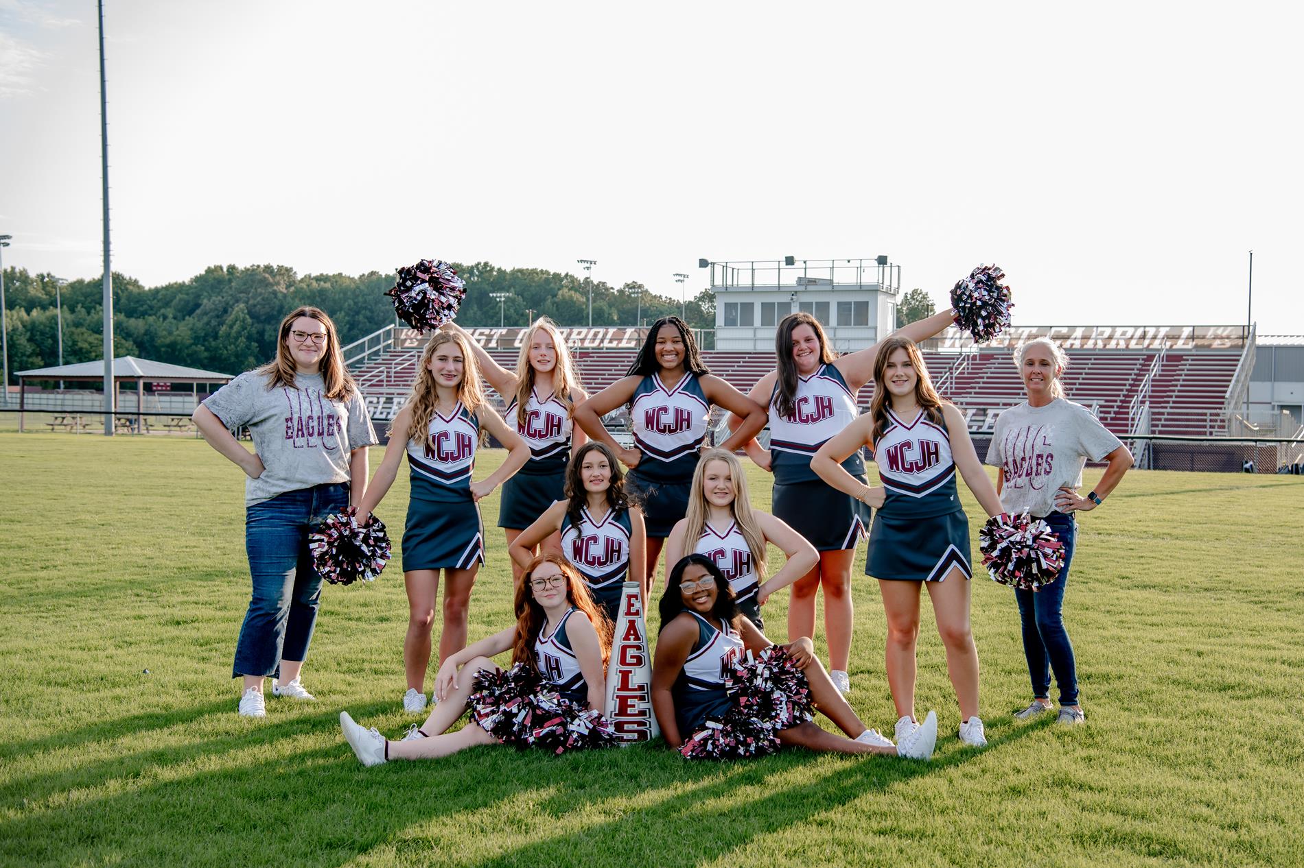 Jr High Cheerleaders posing on football field with coaches