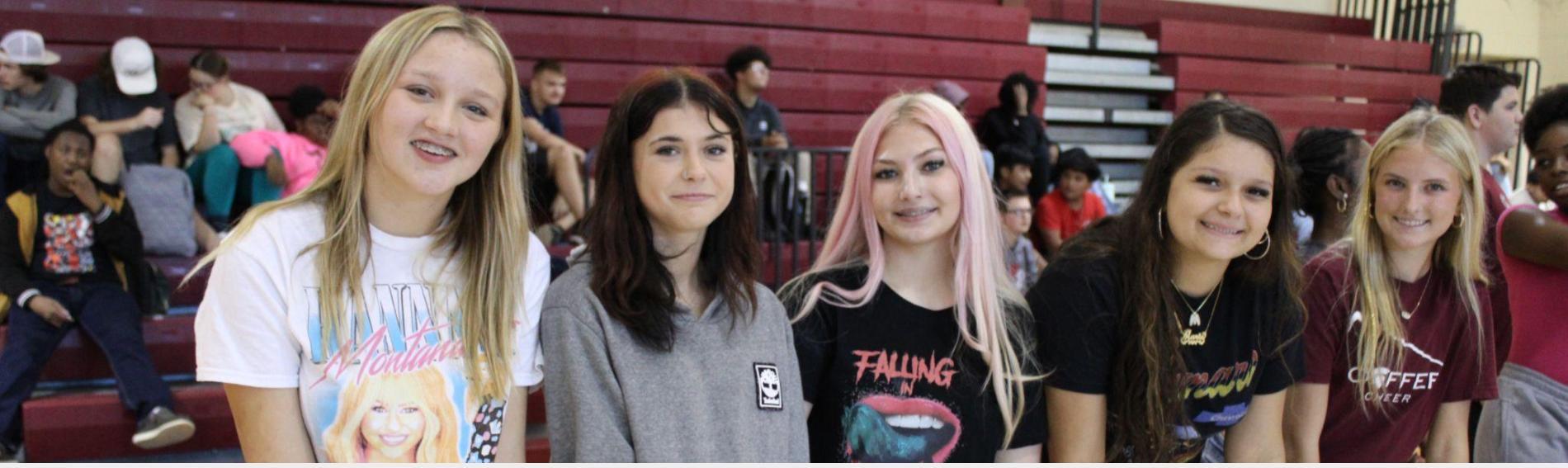 Five girls stand in a line smiling at the camera