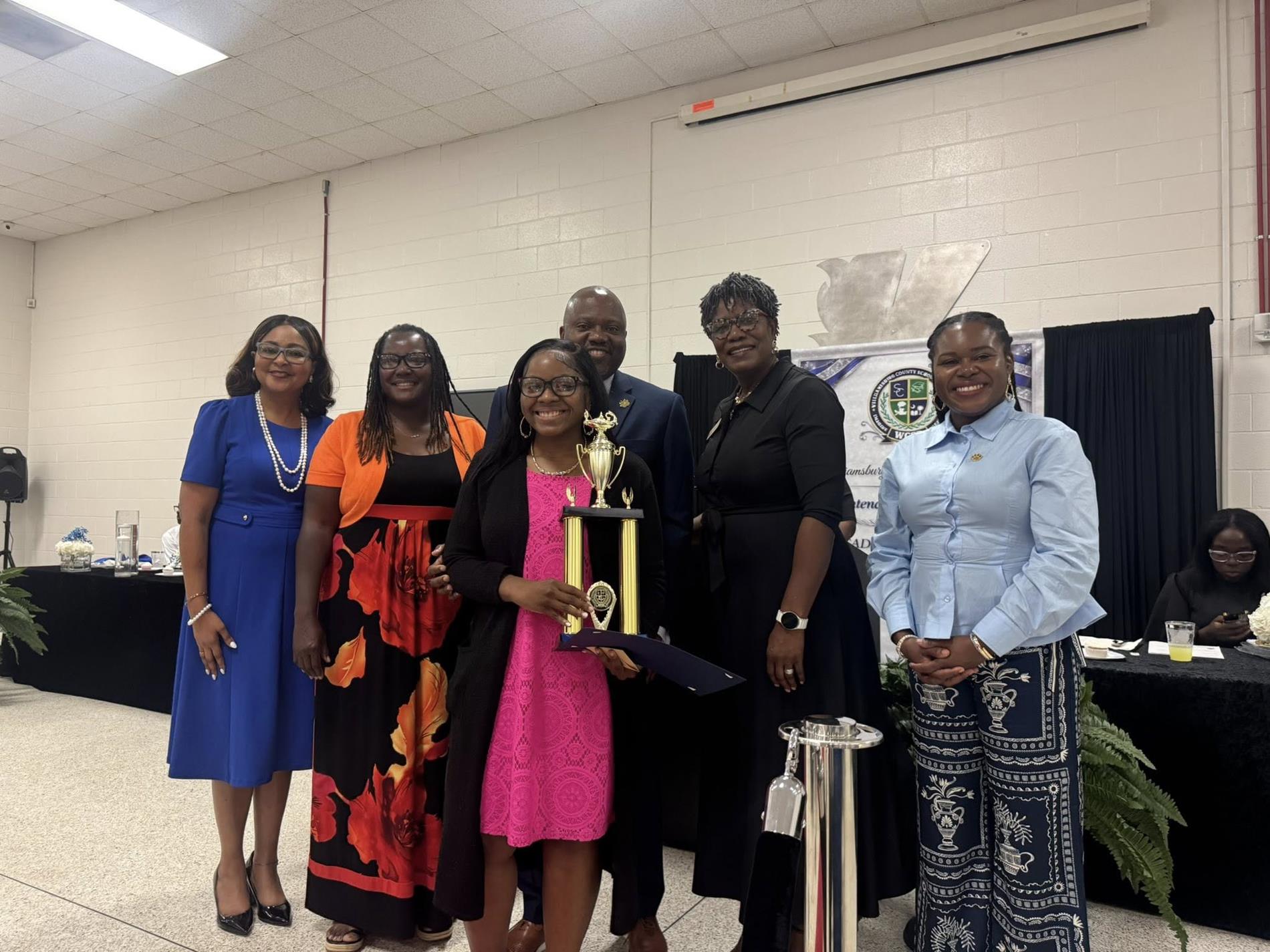 people standing together. one is receiving an award 