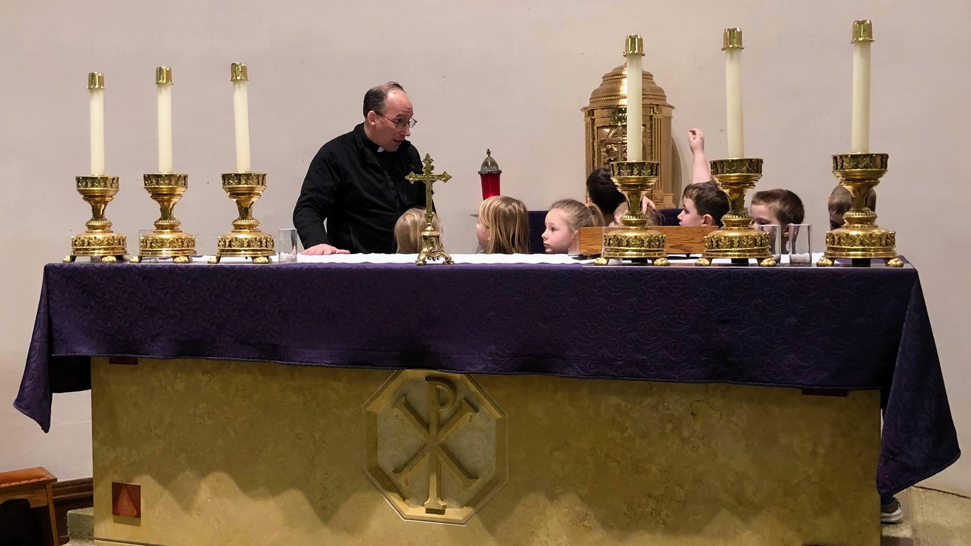 Priest at the altar showing students the tabernacle.