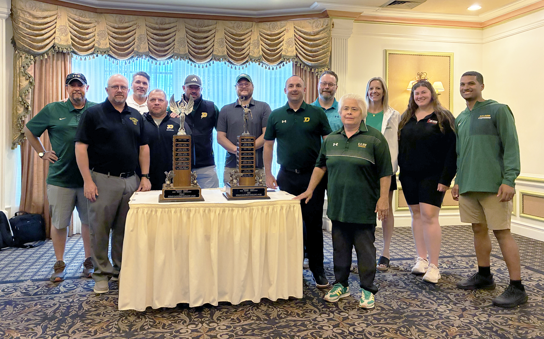 Dow High Athletics Department members stand with the Richard M. Leach trophies in a ballroom