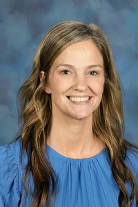 Teacher smiling against a blue background