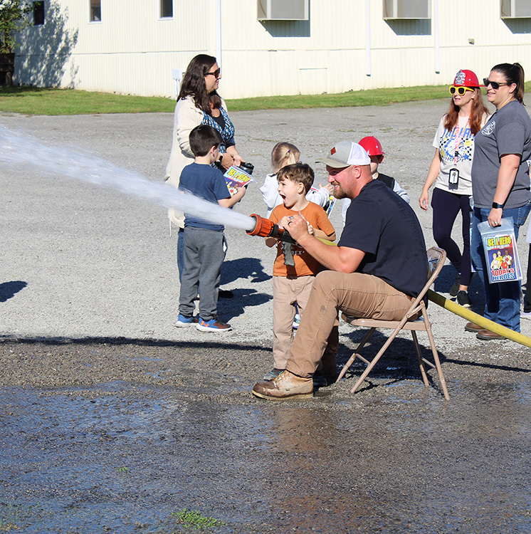 Fire Fighter Andrew Russell helps students with the fire hose