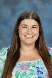 Teacher smiling against a blue background