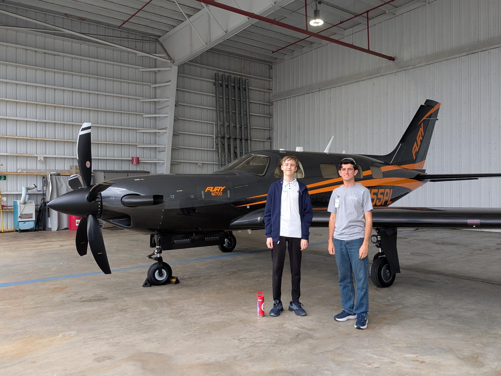 Students standing in front of Piper airplane 