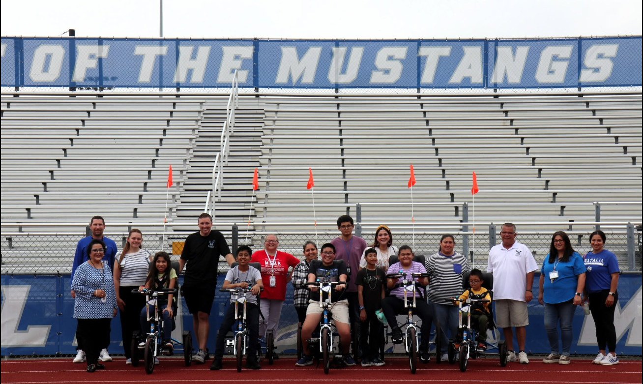 A group of students and teachers holding a mustang relay banner