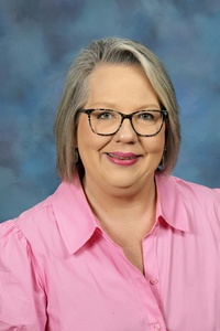 Teacher smiling against a blue background