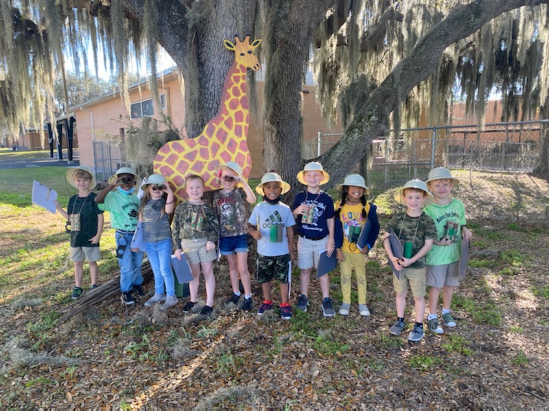 Students standing in front of the giraffe they found on their safari. 