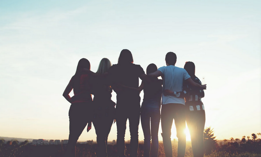 Youth with arms around each other watching sunset Youth with arms around each other watching sunset
