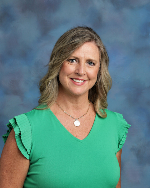 Teacher smiling against a blue background