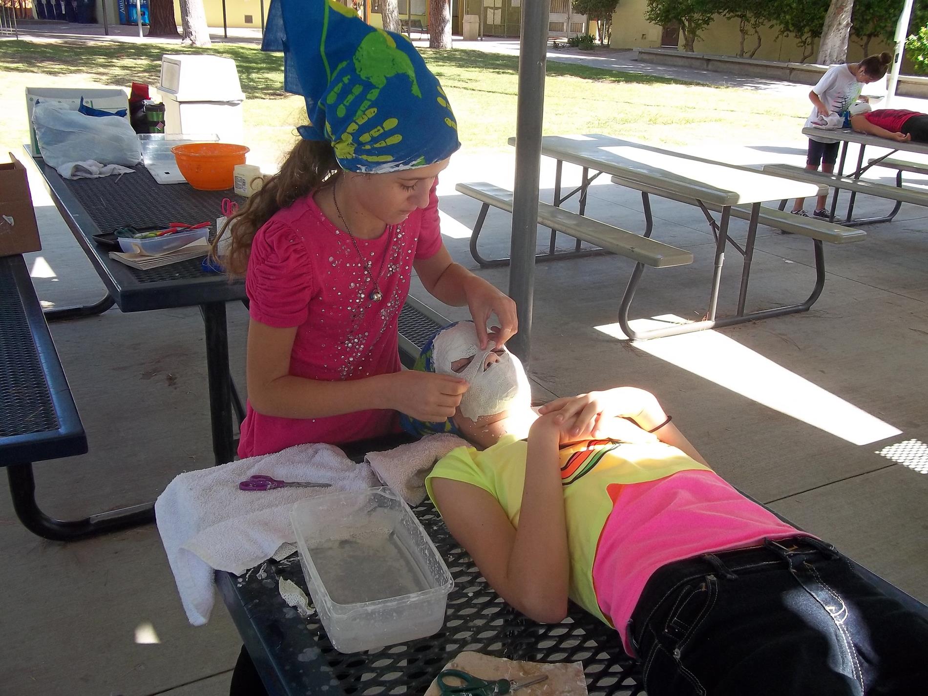 student putting facemask on another student