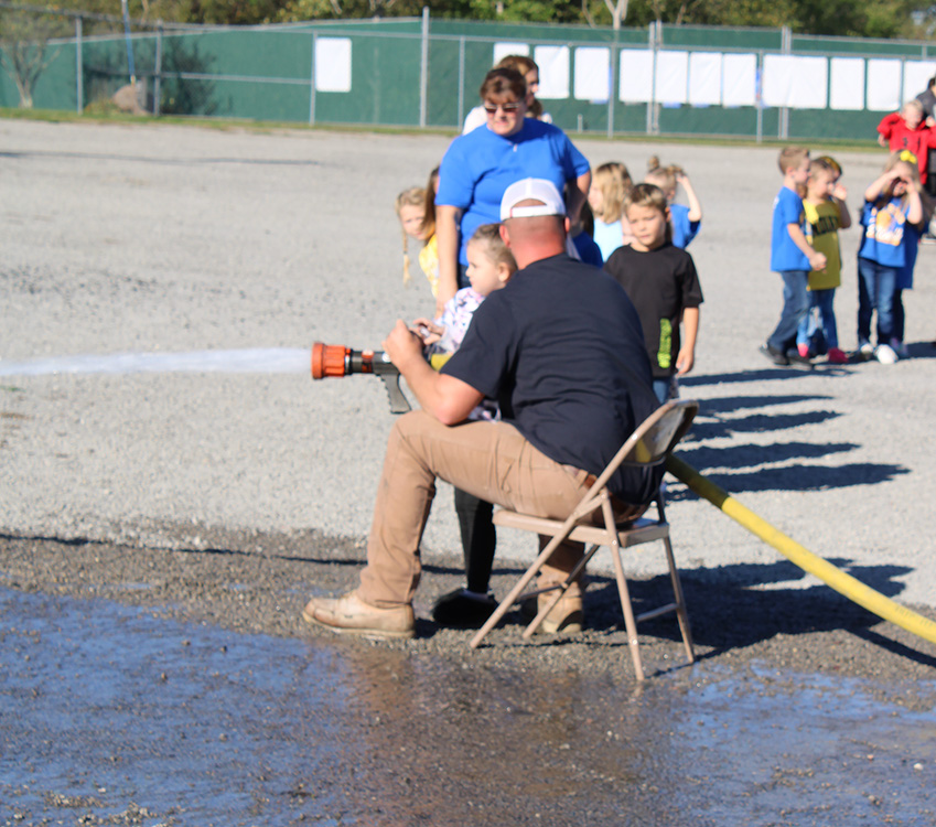 Fire Fighter Andrew Russell helps students with the fire hose