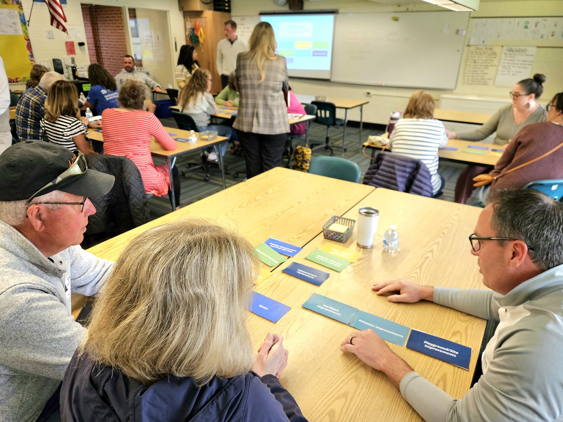 Three community members discuss their selections for bond priorities at a table in a classroom
