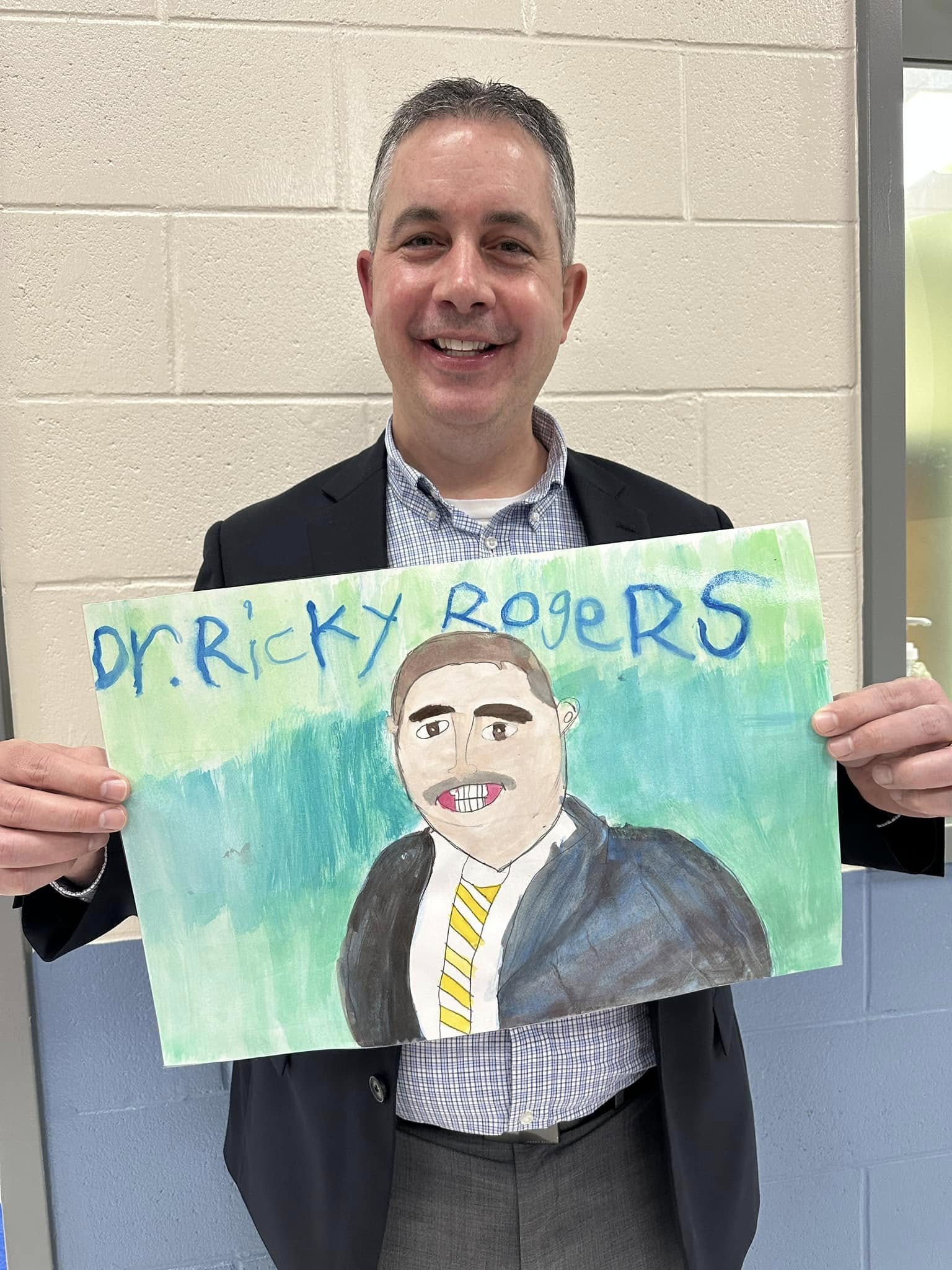 Dr. Rogers holding a picture drawn by a student.