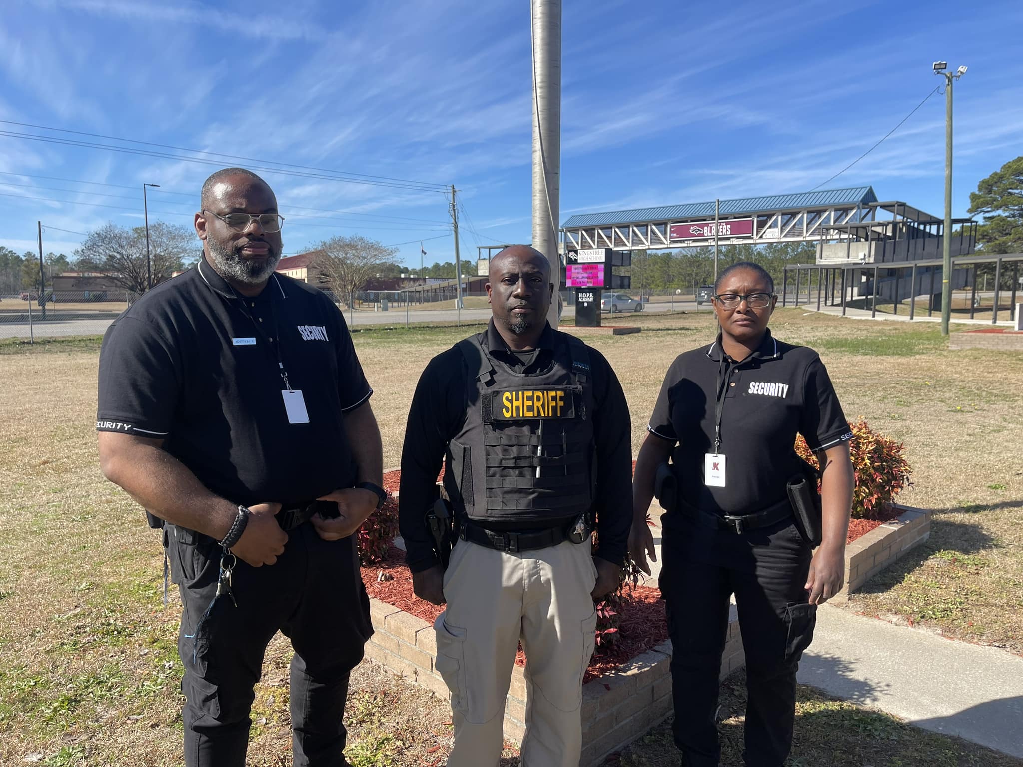 three officers standing together on school yard 