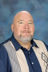 Teacher smiling against a blue background