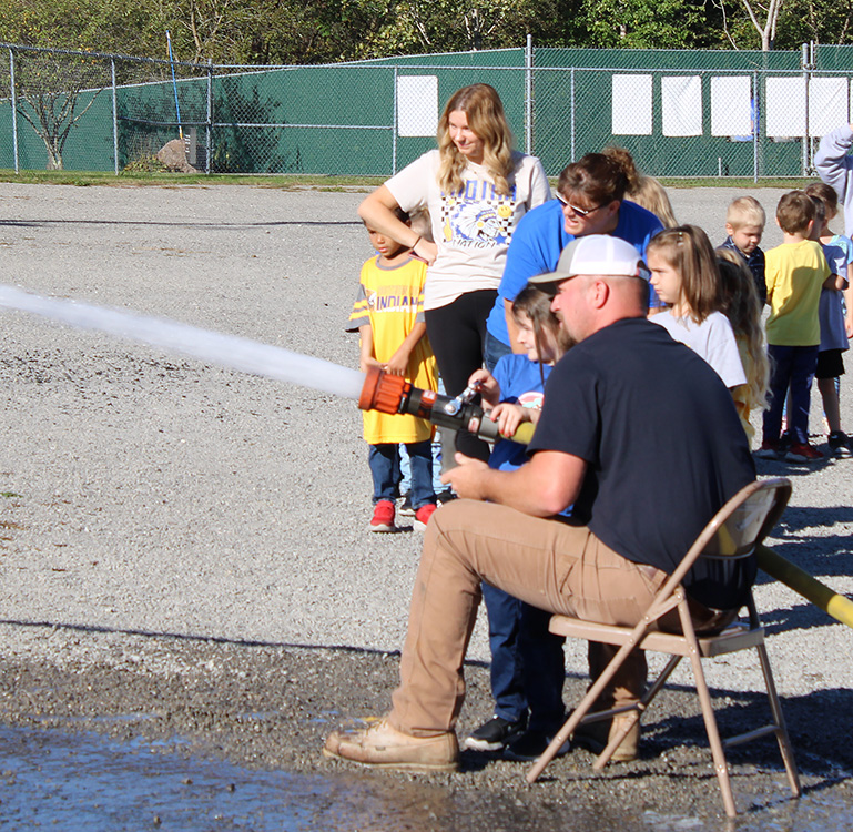 Fire Fighter Andrew Russell helps students with the fire hose