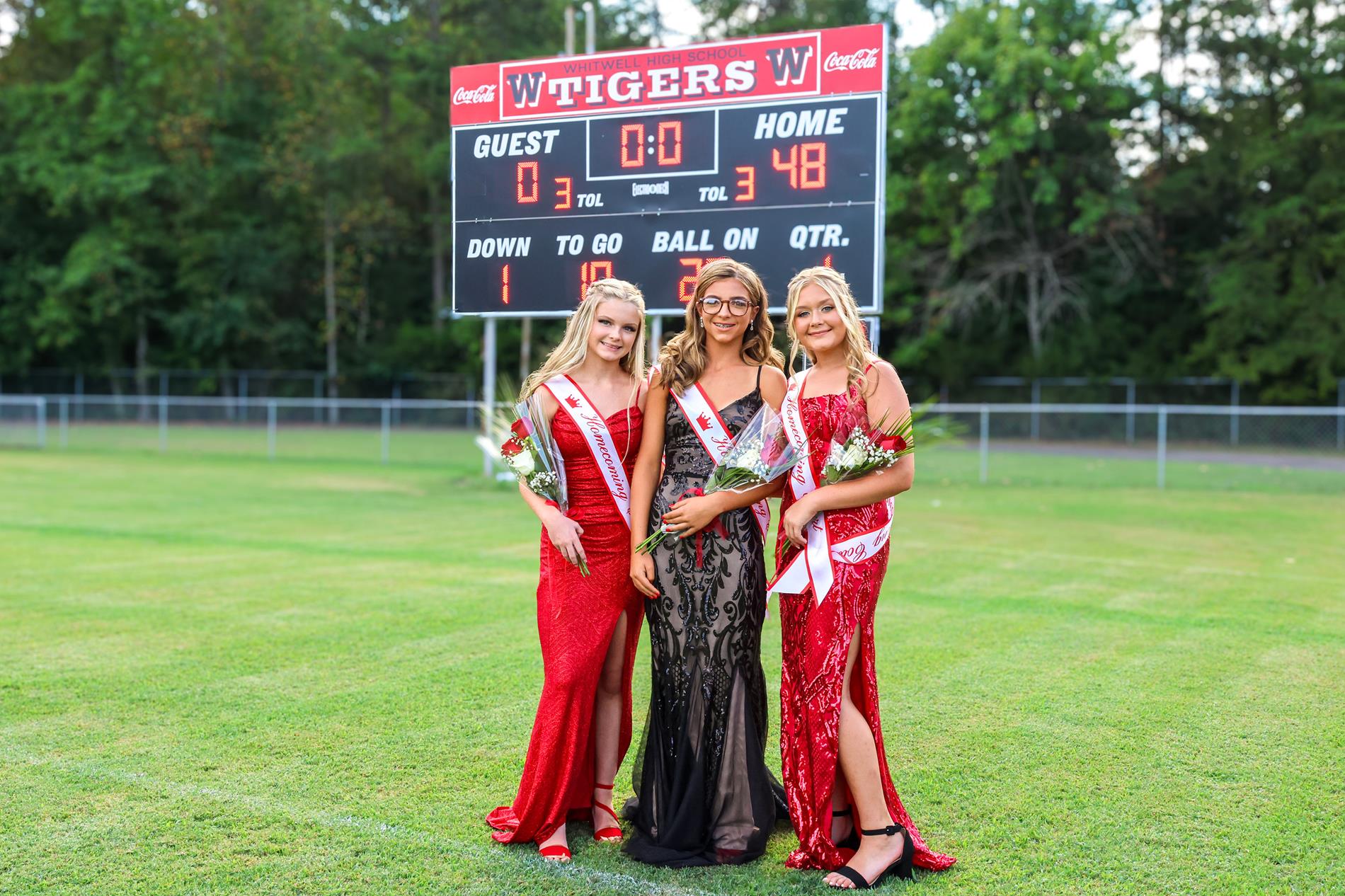 8th grade girls for homecoming court in red and black dresses with red roses