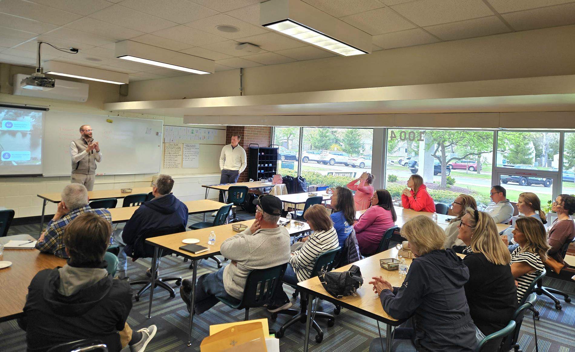 A group sits in a classroom at Northeast listening to a presentation by GMB