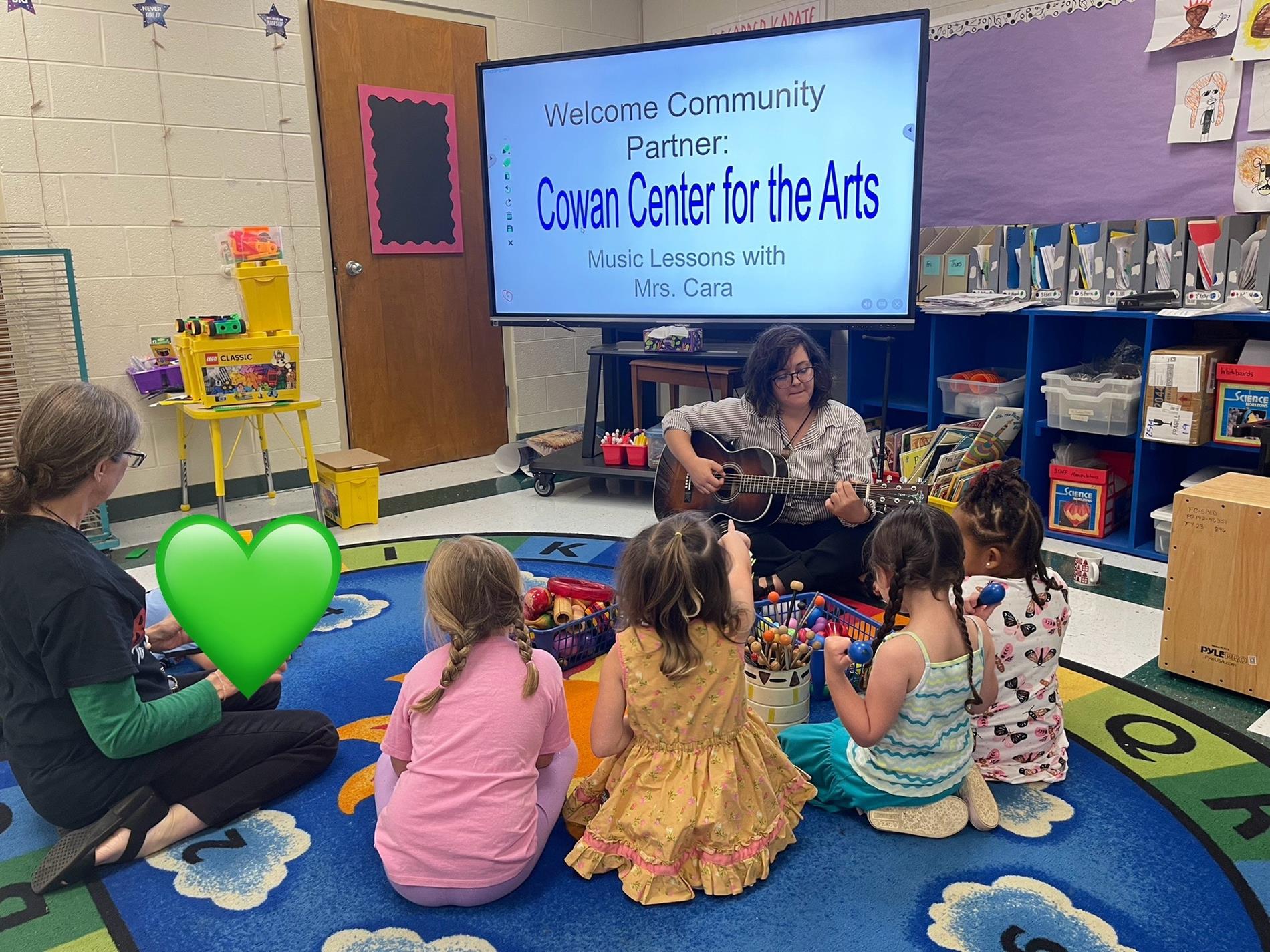 Mrs. Cara and students listening to the guitar