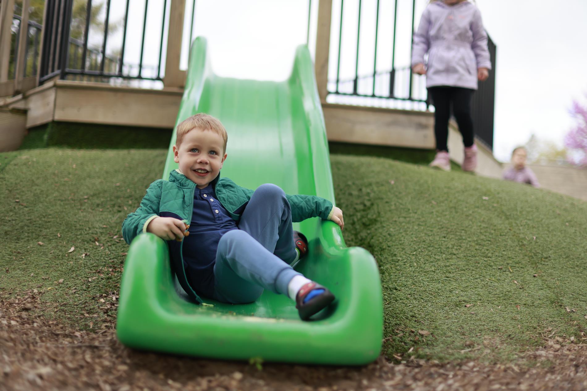 A young boy on a green slide at the Carpenter Pre-Primary Center