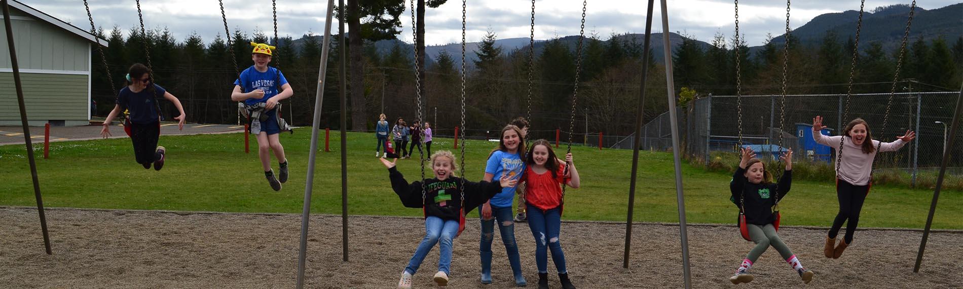 Third and fourth grade students swinging at recess
