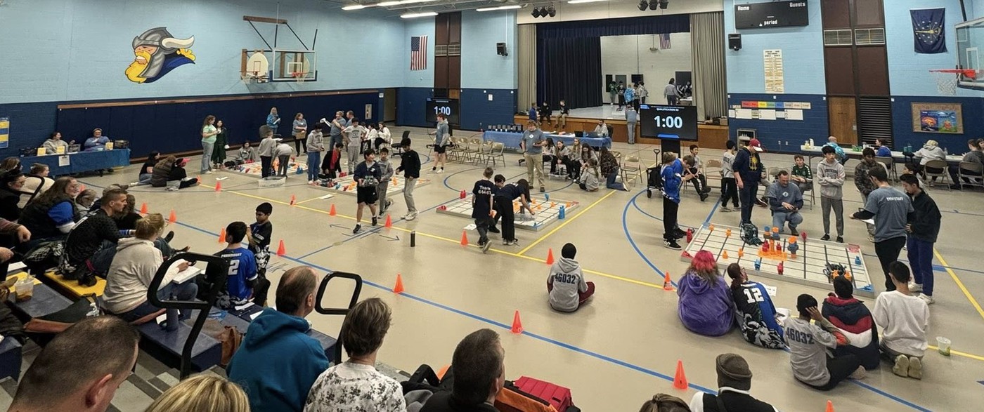 Wide shot of MCS gym during a robotics tournament.
