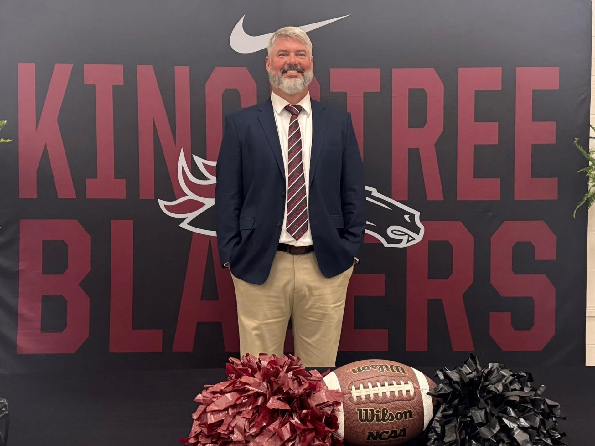 white male standing in front of backdrop check mark symbol. kingstree blazers. horse logo