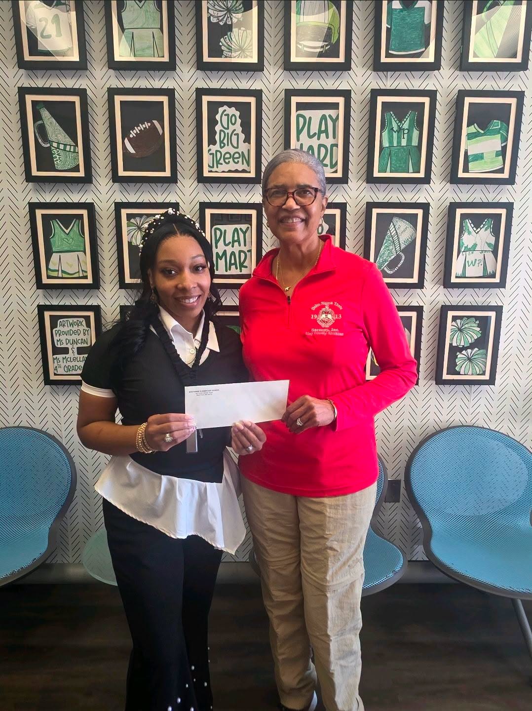 A South Side Elementary staff member accepts a donation from a representative of the Clay County Alumnae Chapter of Delta Sigma Theta Sorority, Inc. to support the school’s PBIS program.