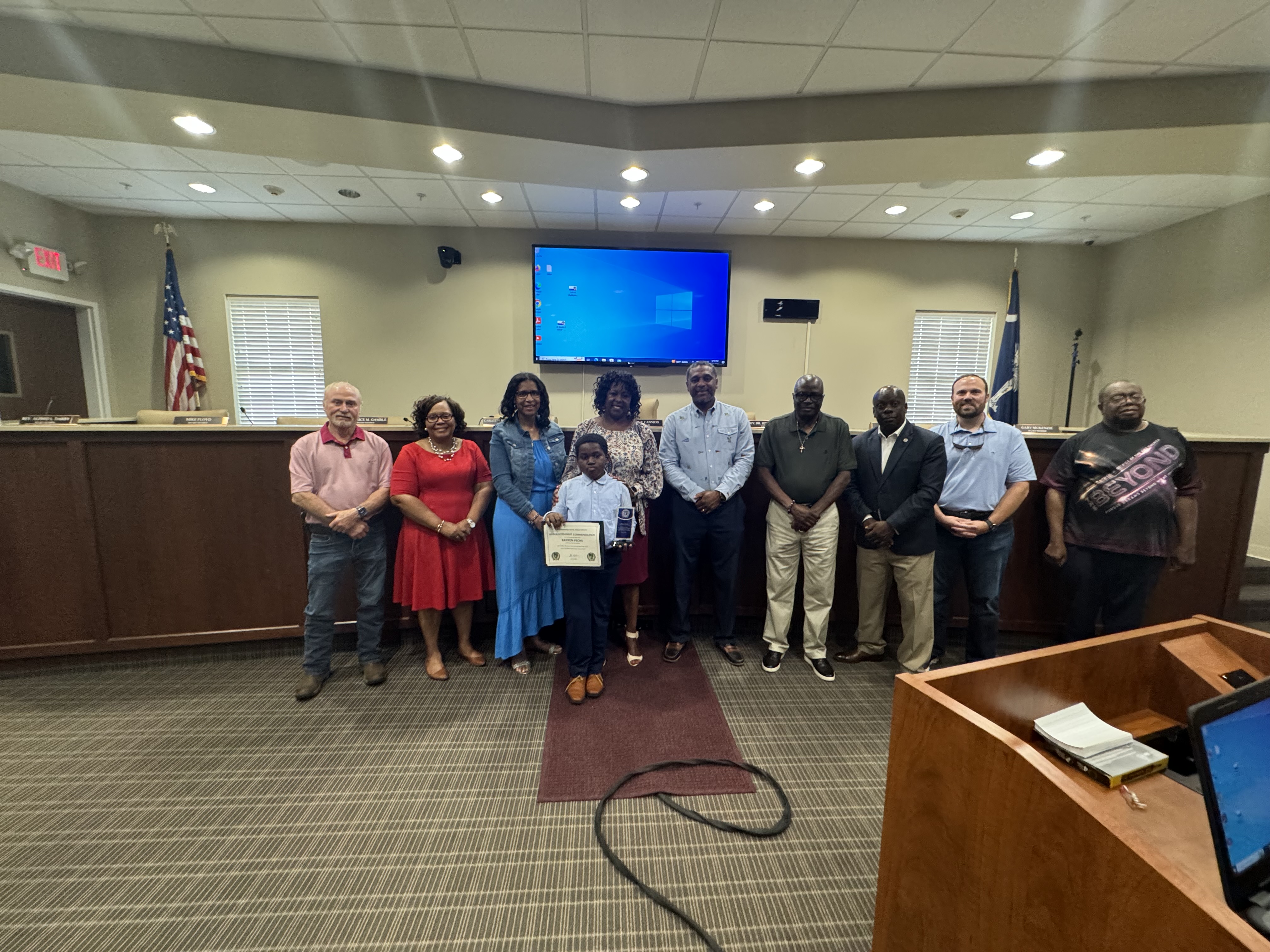 Student being recognized for his academic achievement pictured along with school board members 