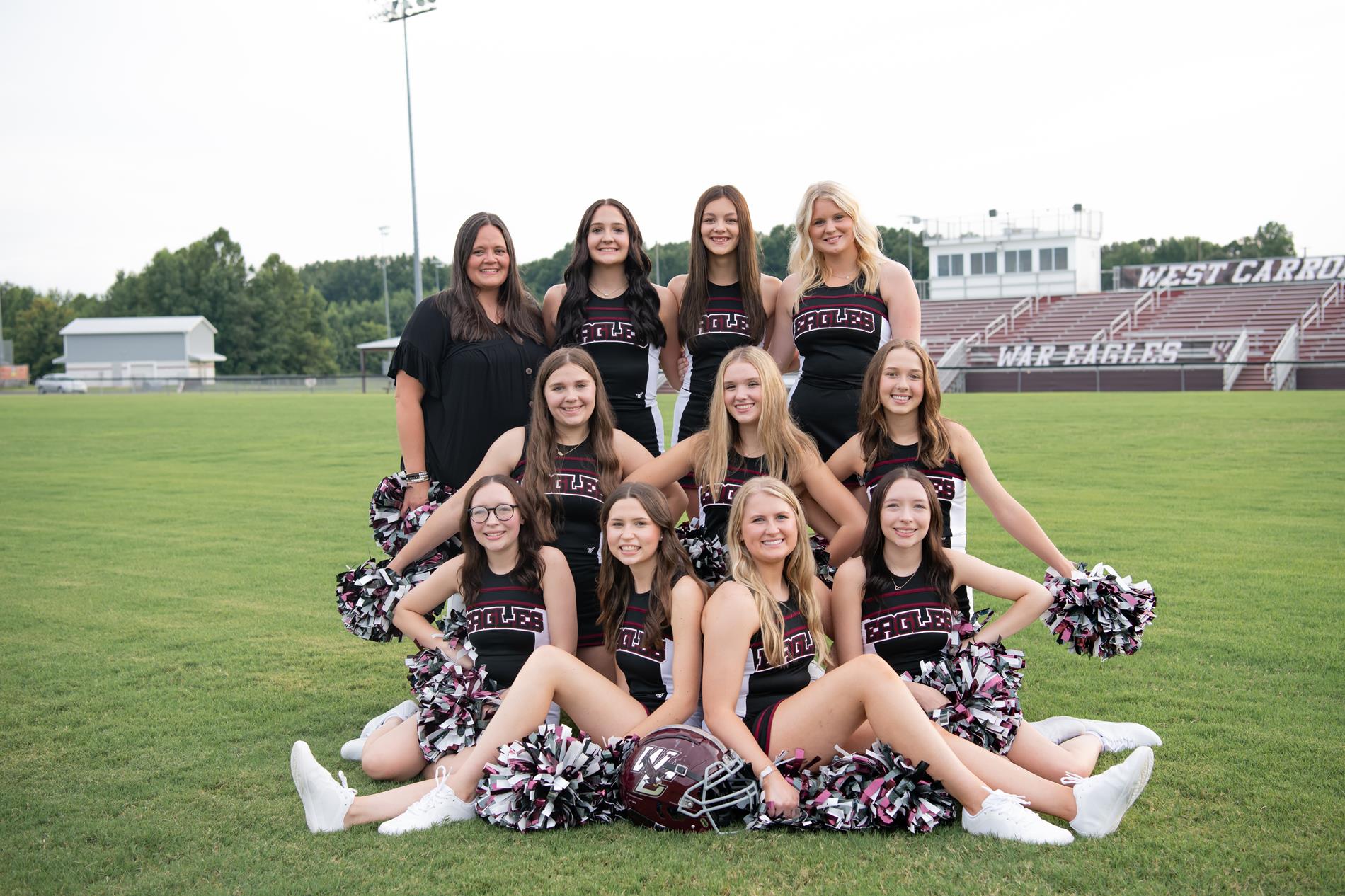 HS Cheerleaders posing on football field with coach