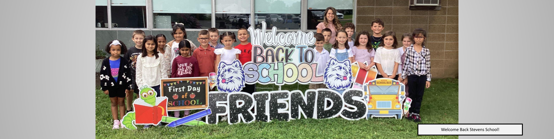 Whole class posing in front of the welcome back to school signs