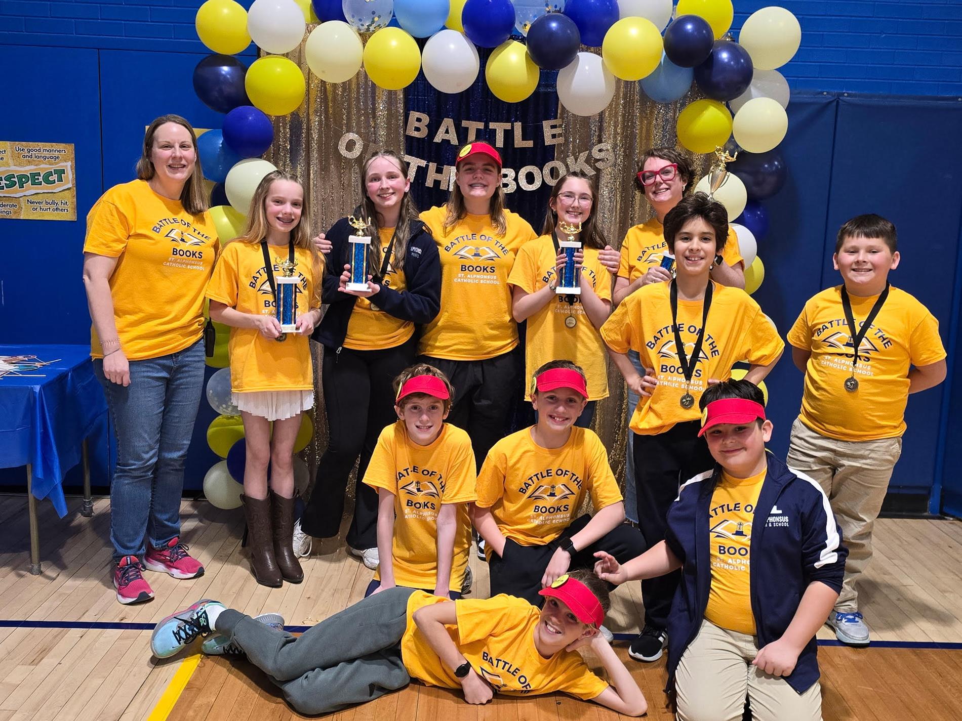 students in front of a backdrop smiling with trophies