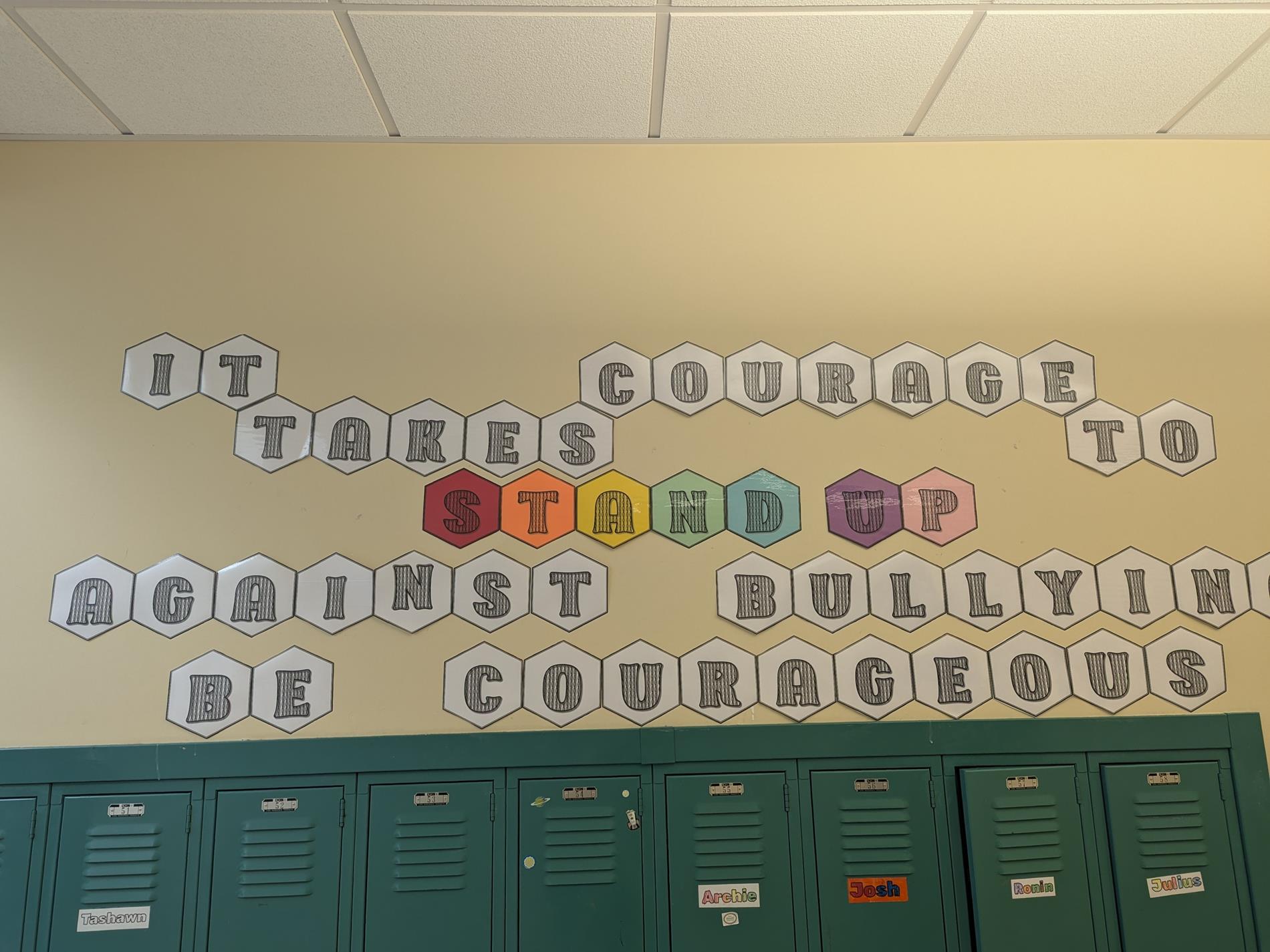 Image of sign above lockers. Sign reads "It takes courage to stand up against bullying. Be courageous"