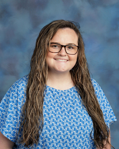 Teacher smiling against a blue background