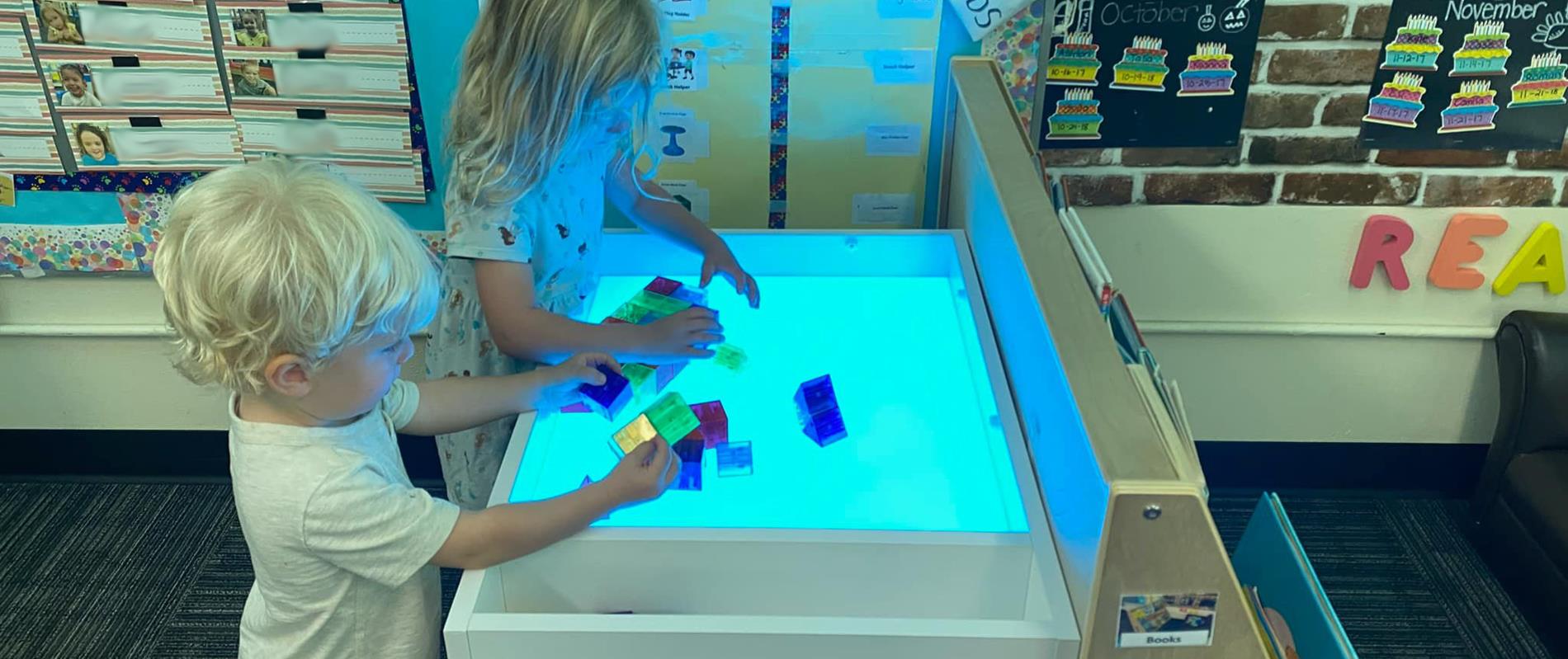 young students playing with blocks on a lightbox