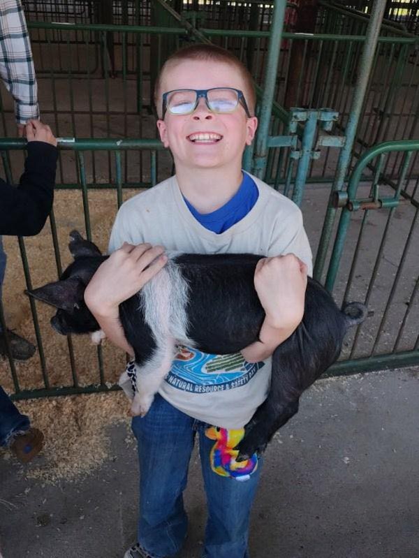 An elementary student holding a piglet in his arms at the 2026 Ag Day show.