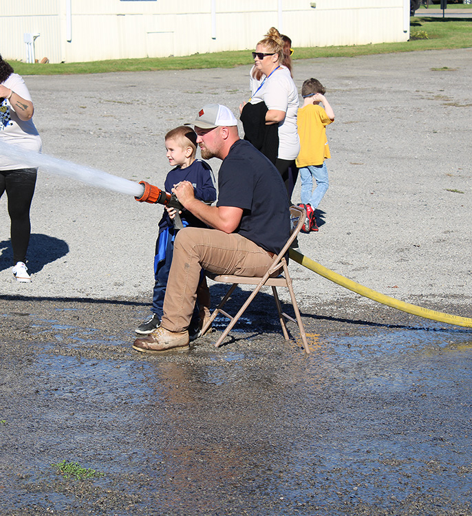 Fire Fighter Andrew Russell helps students with the fire hose