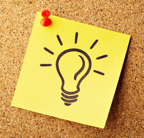 lightbulb on a yellow sticky note pinned to a corkboard