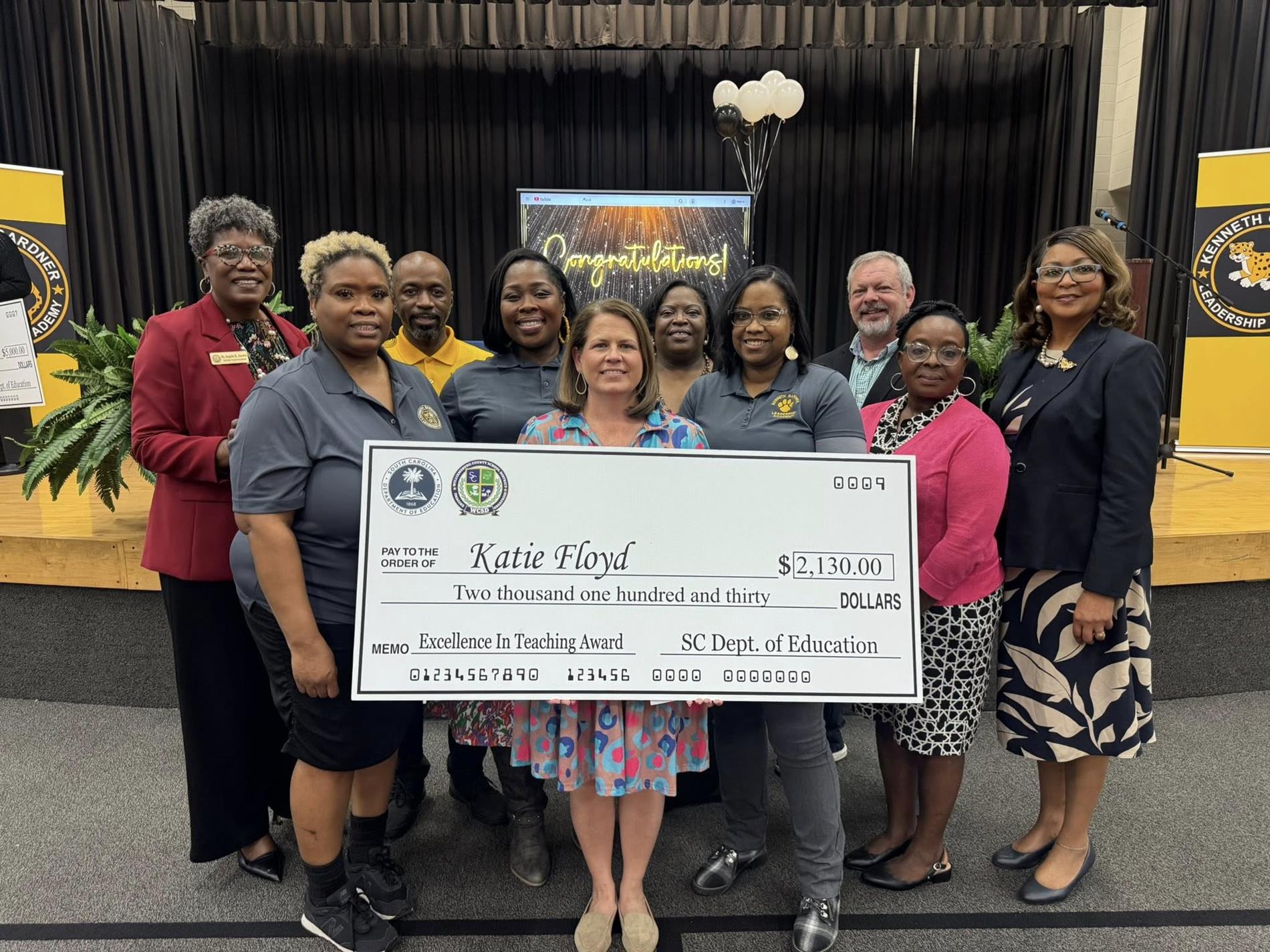 people standing holding large check 