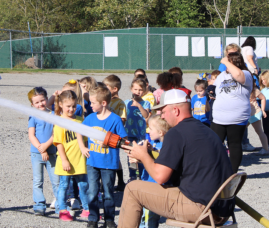 Fire Fighter Andrew Russell helps students with the fire hose