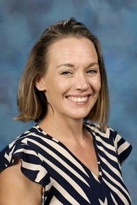 Teacher smiling against a blue background