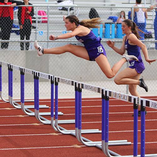 Girl jumps over hurdle
