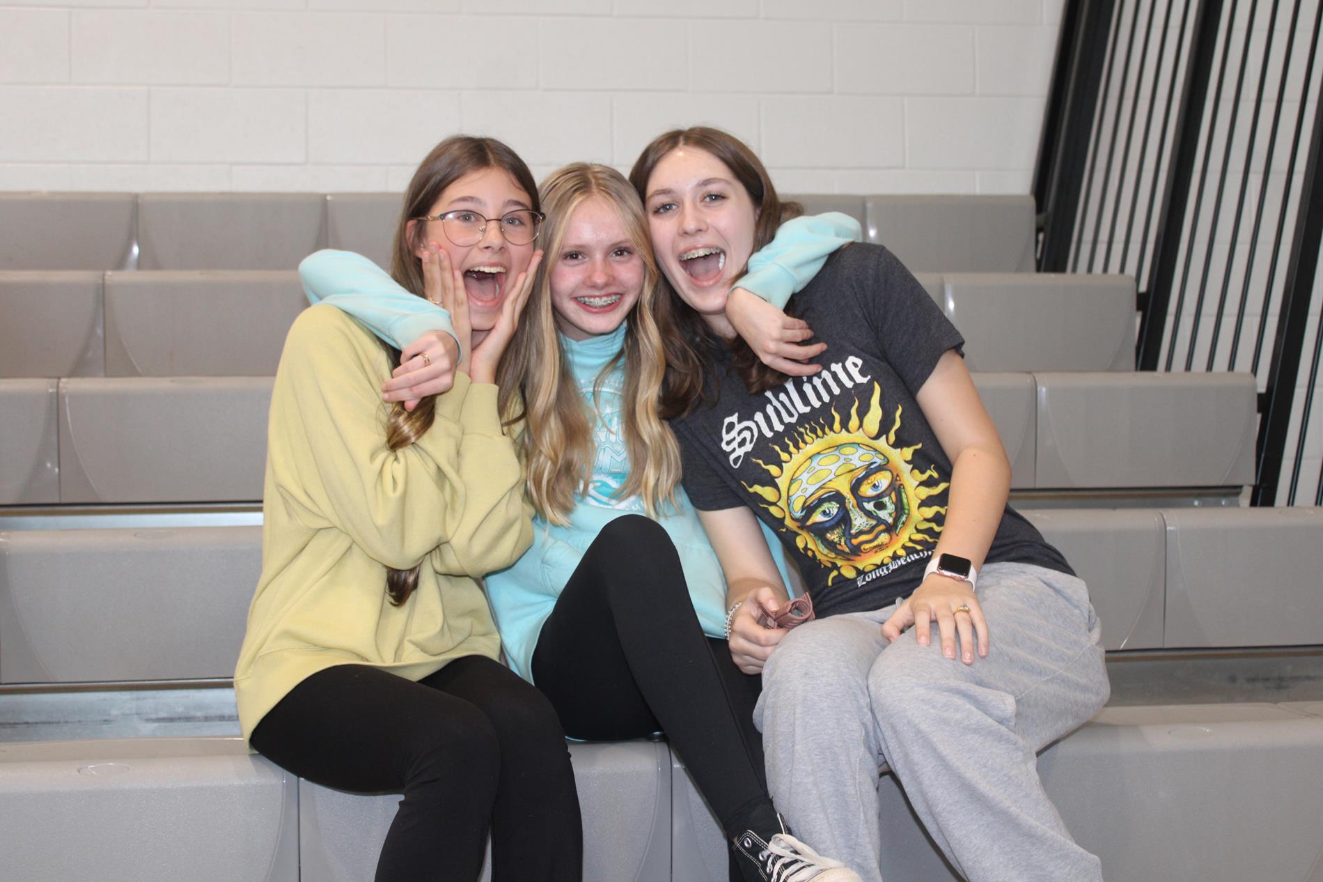 three female students sitting together on bleachers