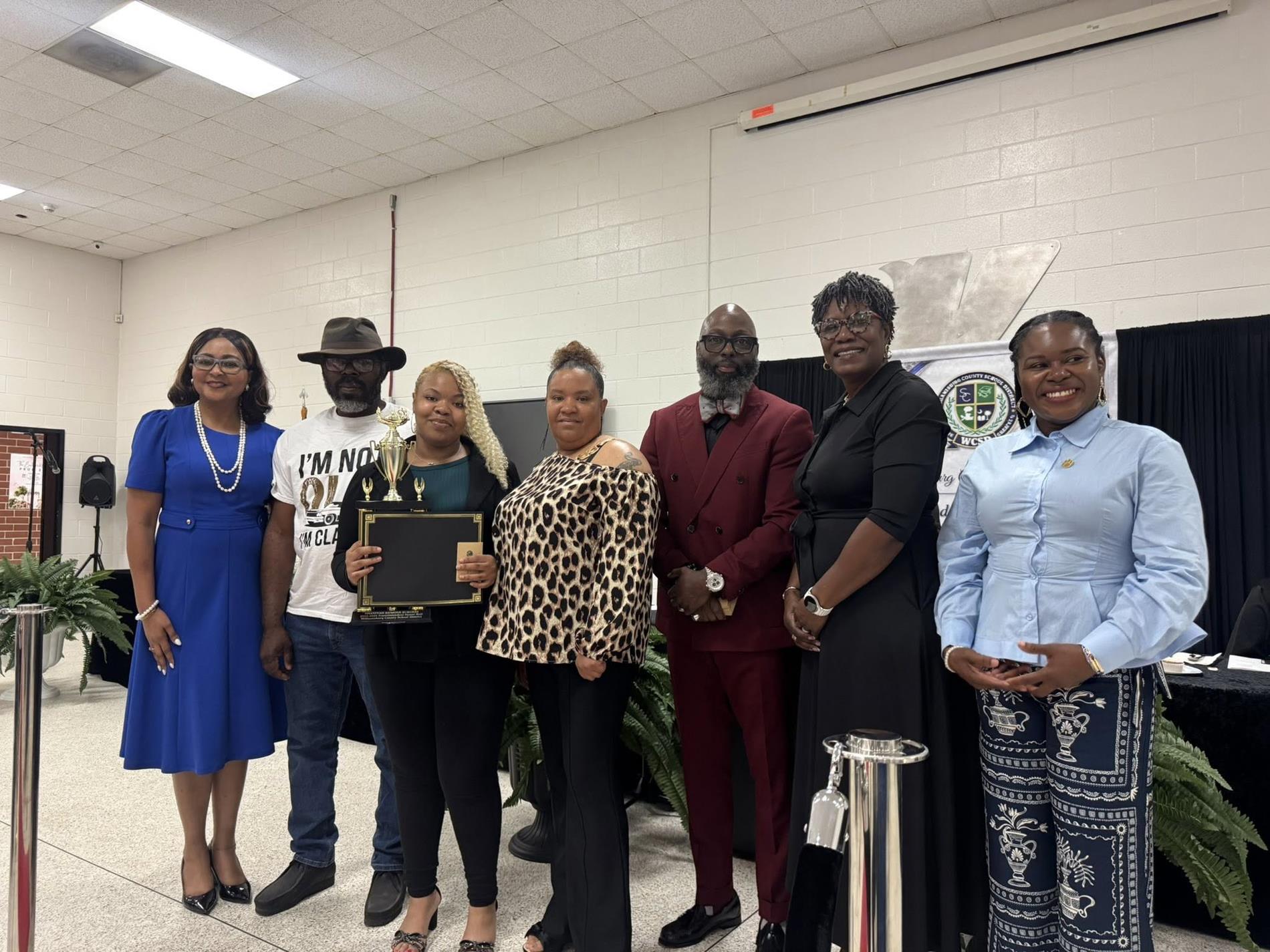 people standing together. one is receiving an award 