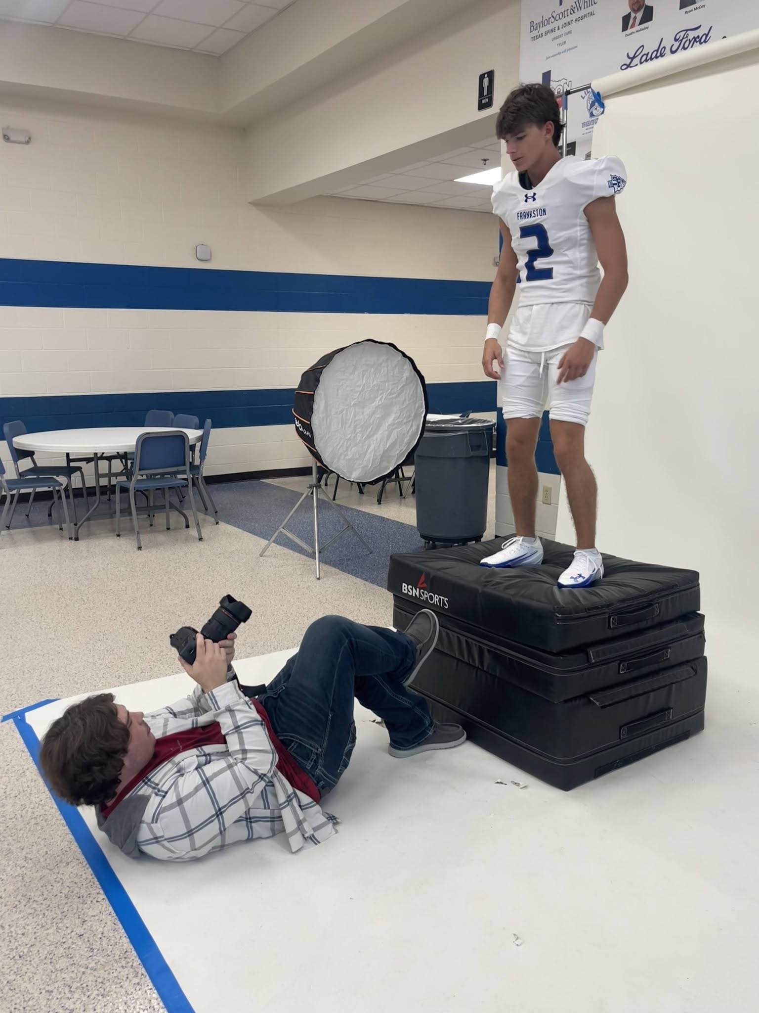 Photography students taking pictures of football students at media day